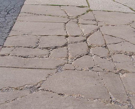 a section of sidewalk in which the concrete is broken into many pieces