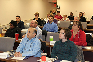 Residents seated at long tables listen to a presentation