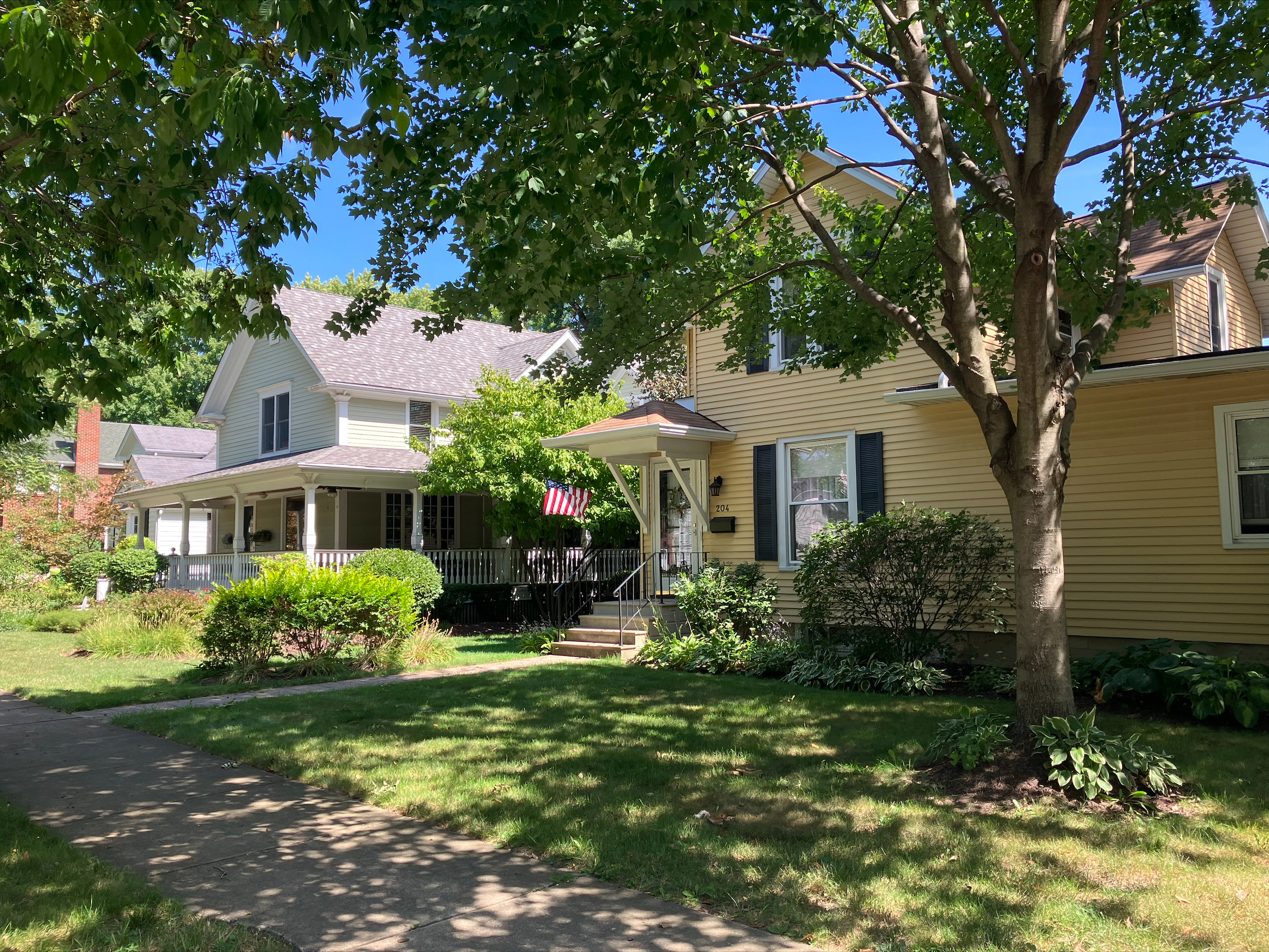 A yellow house with green shutters displays a flag in Naperville's historic district.