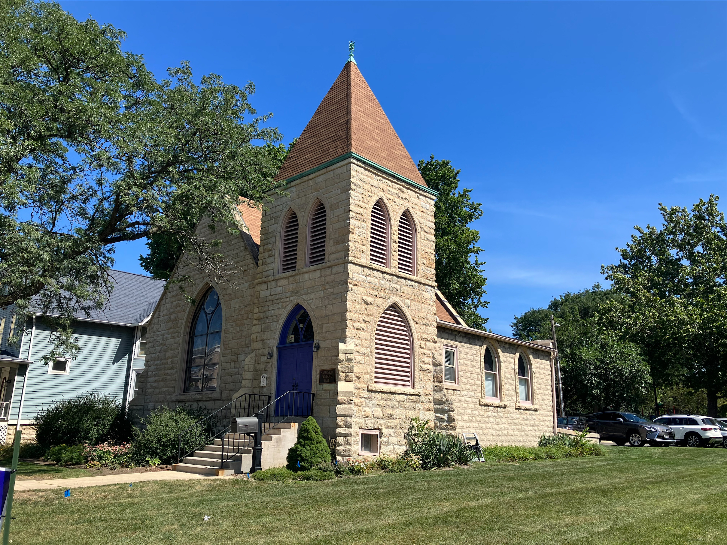 a Gothic revival church surrounded by grass and trees